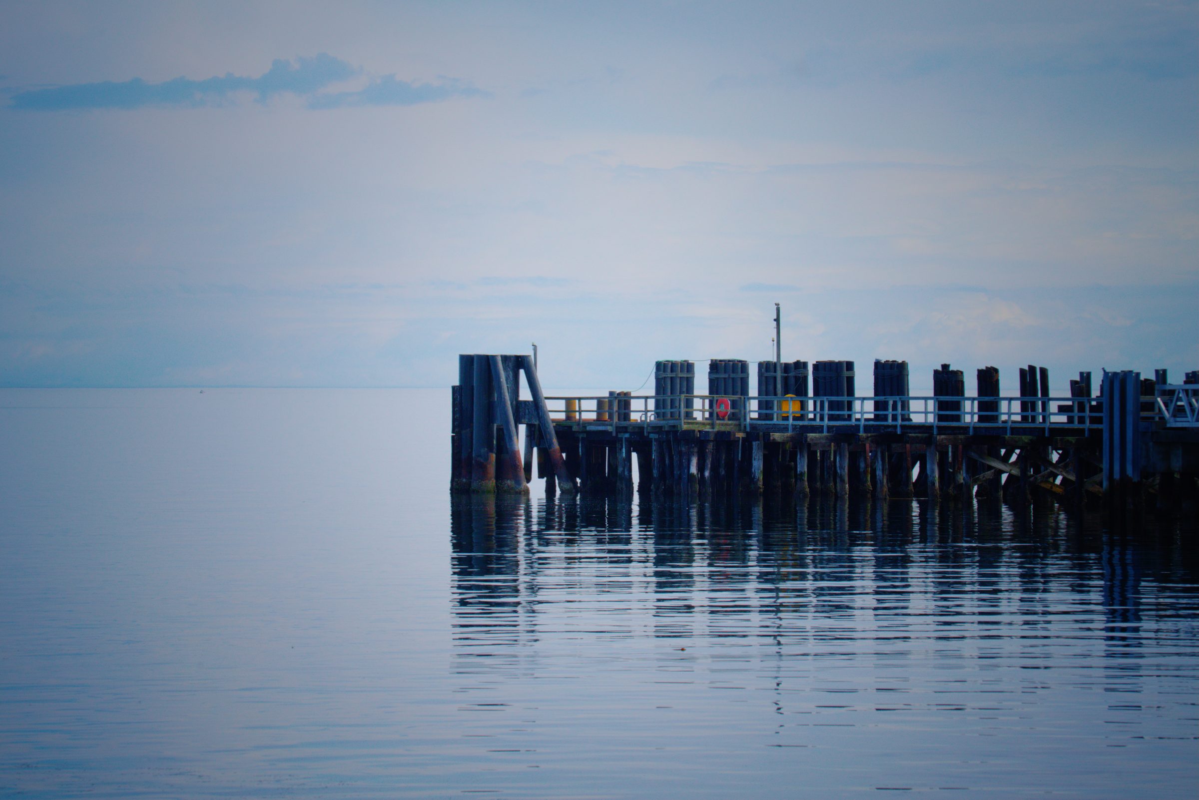 The same pier as the photographer finished it, in a cooler, deeper blue with darkened edges.