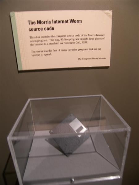 A floppy disk in a clear display case at the Computer History Museum, under a placard reading The Morris Internet Worm source code.