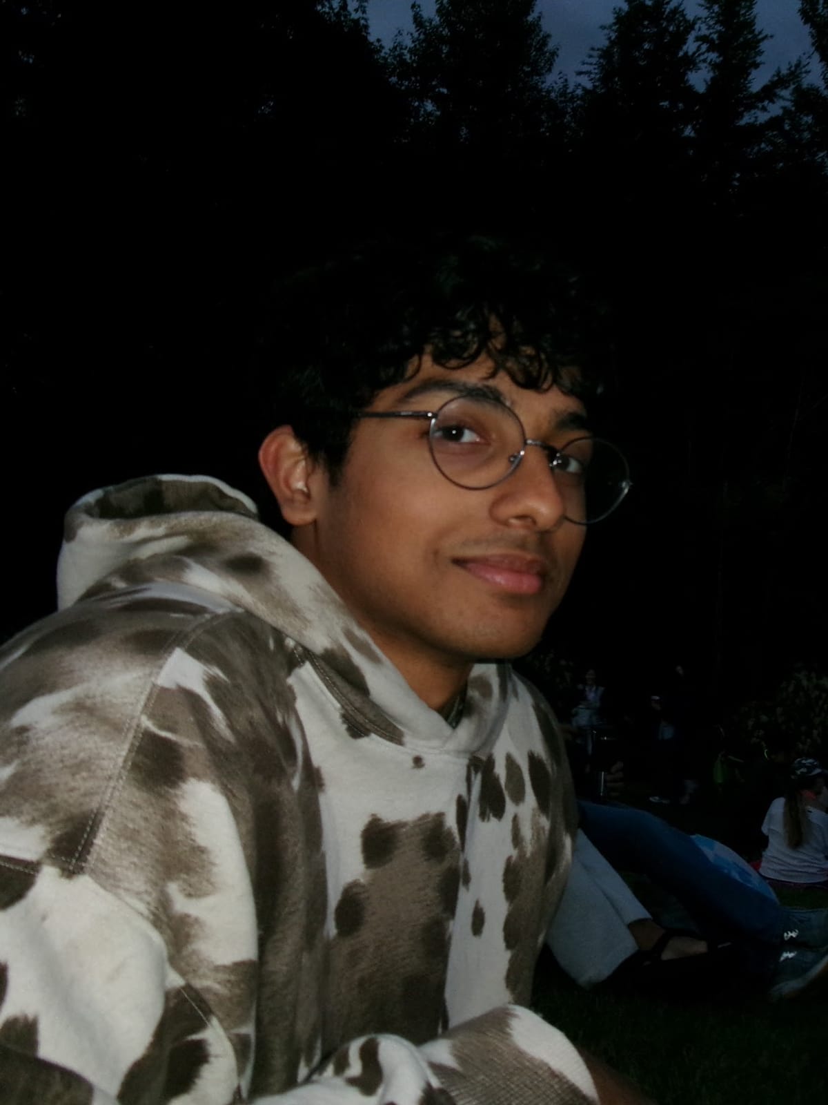 Aditya at dusk in a patterned hoodie, glancing at the camera